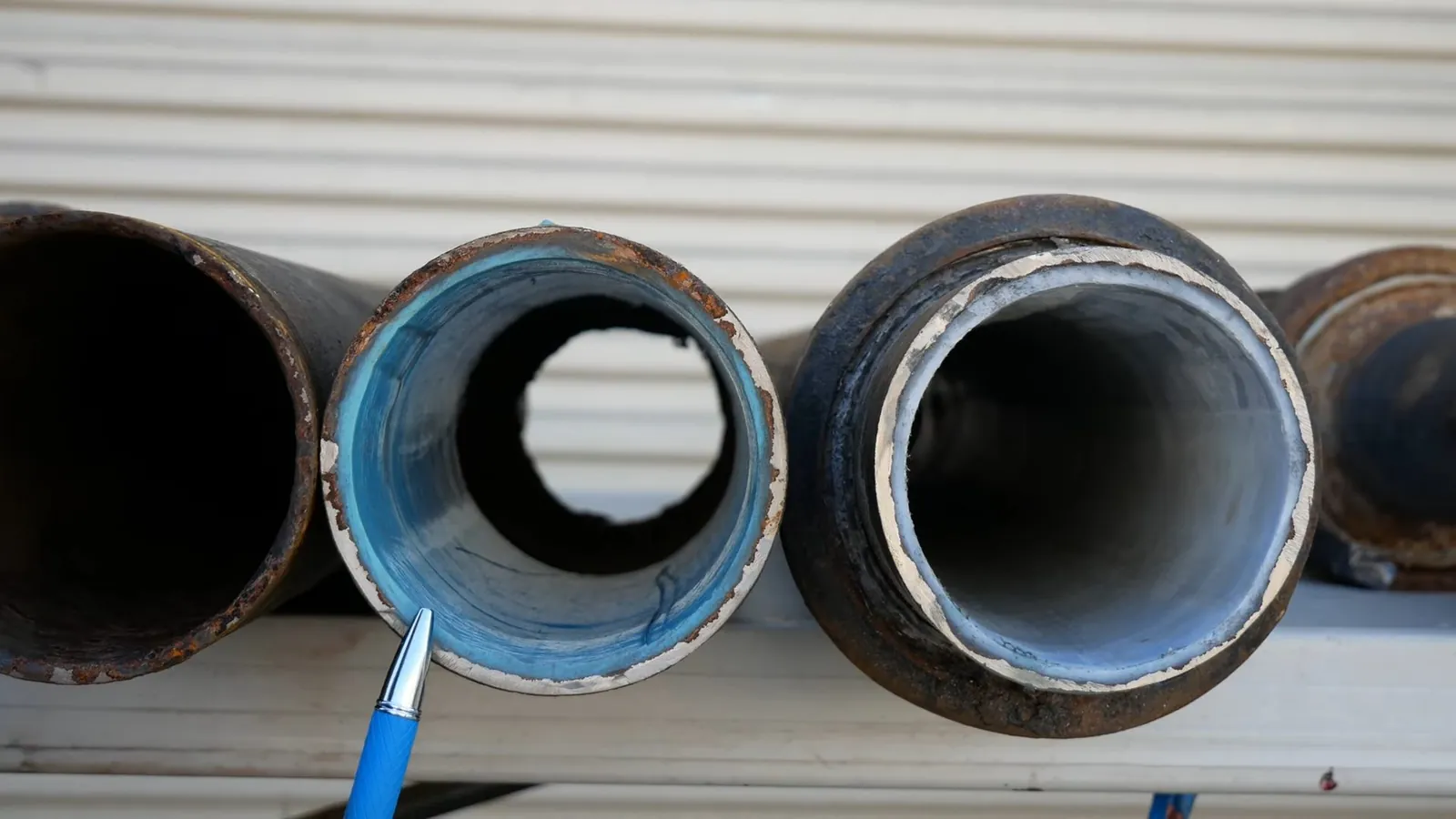Cut ends of black pipe showing a blue epoxy liner on the inside