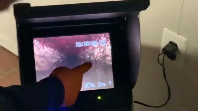 Finger pointing at the screen of a sewer camera monitor showing the inside of a pipe