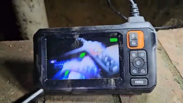 Handheld inspection camera showing a live view of the inside of a pipe on its screen