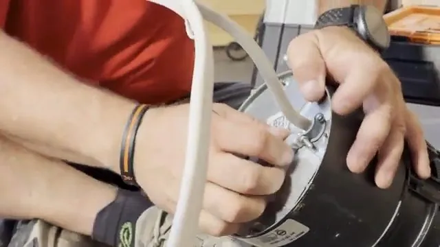 Hands fitting a garbage disposal unit onto its mounting ring under a sink
