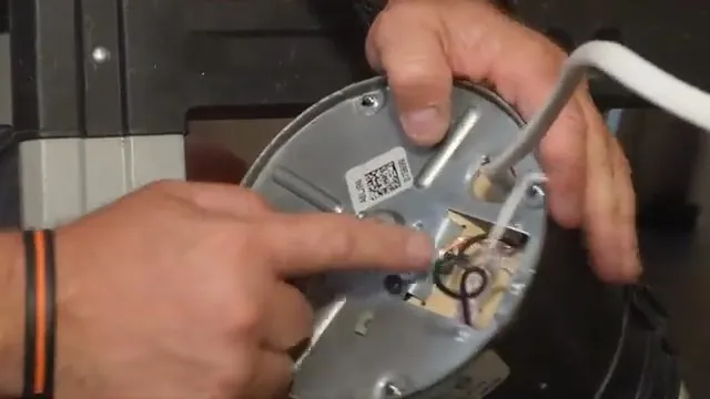 Hands pointing to the underside of a garbage disposal where an Allen wrench fits