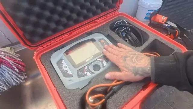 Open red hard case holding a sewer camera monitor with its cables