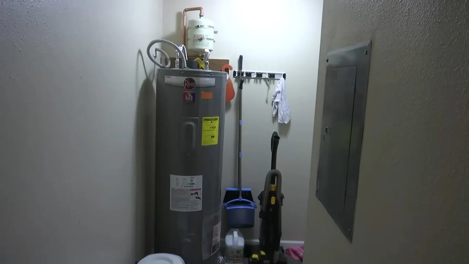 Tank water heater standing in a closet next to an electrical panel