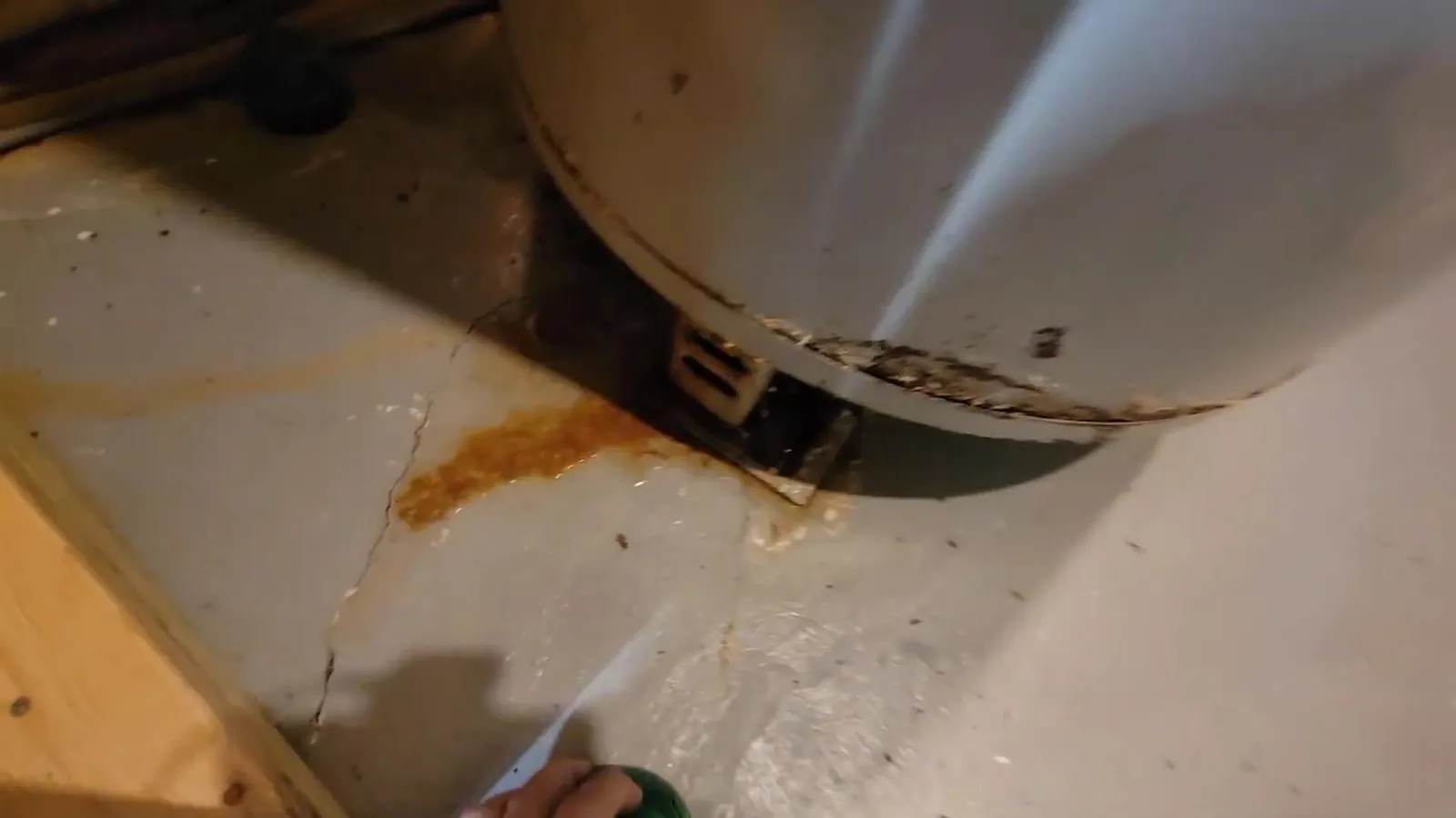 Rust stain on the floor beneath the base of a water heater tank